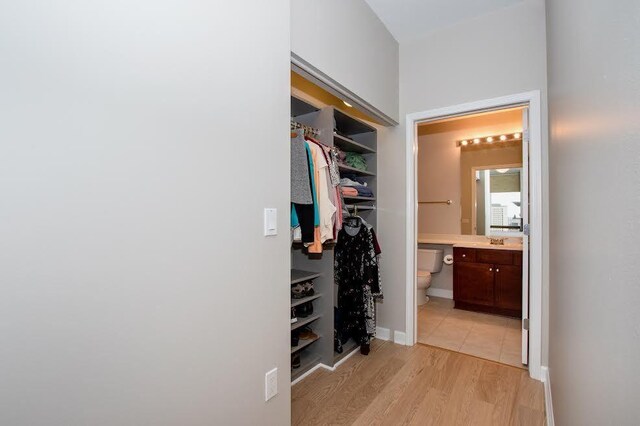 walk in closet with light hardwood / wood-style floors and sink