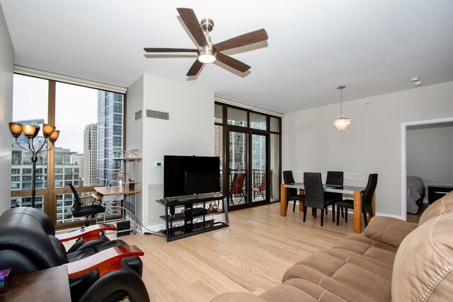 living room with ceiling fan, floor to ceiling windows, and light hardwood / wood-style flooring