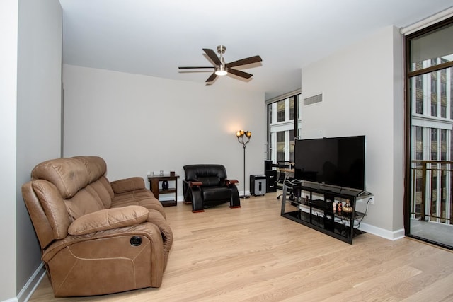 living room featuring a wall of windows, ceiling fan, a healthy amount of sunlight, and light wood-type flooring