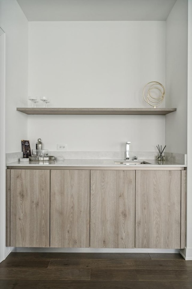 bar with light brown cabinets, dark hardwood / wood-style floors, and sink