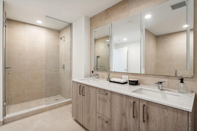 bathroom with tile patterned flooring, vanity, and tiled shower