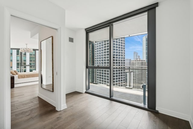 empty room featuring hardwood / wood-style floors, floor to ceiling windows, and a chandelier