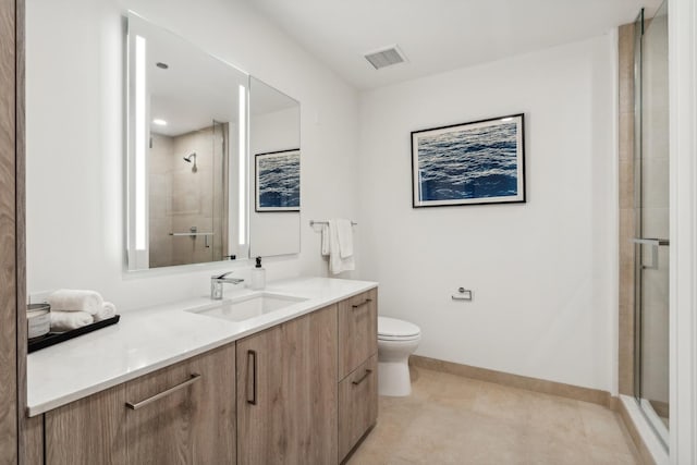 bathroom with tile patterned flooring, vanity, a shower with shower door, and toilet