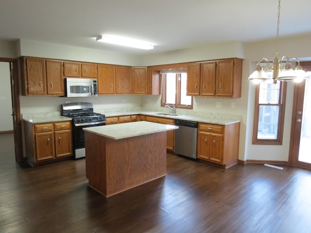 kitchen with gas range, dishwasher, sink, an inviting chandelier, and a kitchen island