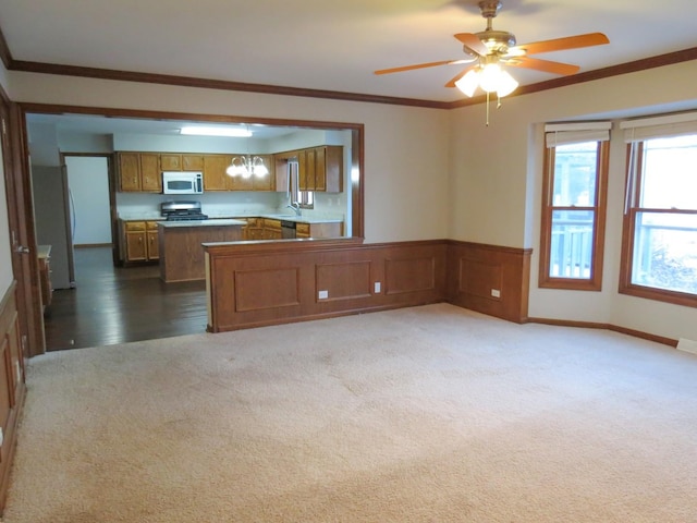 kitchen featuring kitchen peninsula, carpet, stainless steel appliances, and ornamental molding