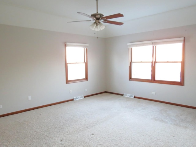 carpeted empty room with a wealth of natural light and ceiling fan