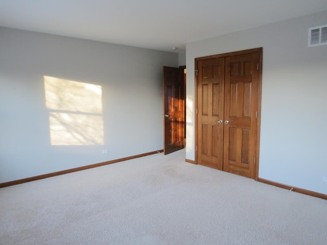 unfurnished bedroom with light colored carpet and a closet