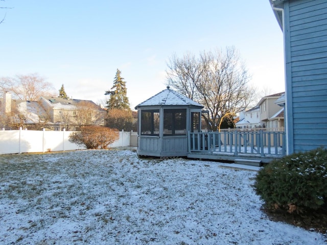 snowy yard featuring a sunroom and a wooden deck