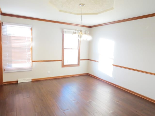 unfurnished room with a notable chandelier, crown molding, dark wood-type flooring, and a tray ceiling