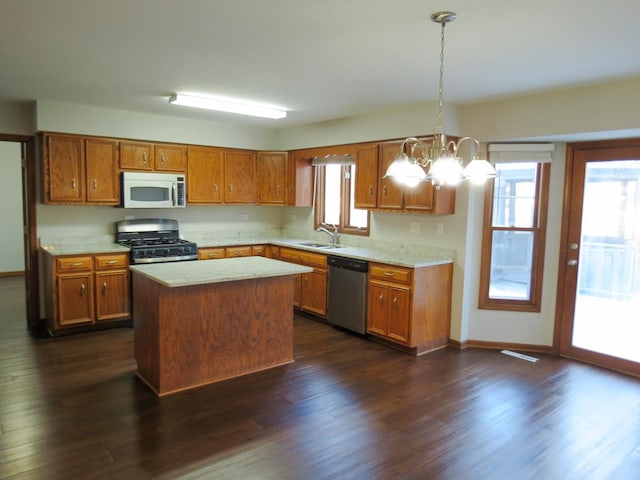 kitchen featuring appliances with stainless steel finishes, pendant lighting, an inviting chandelier, dark hardwood / wood-style floors, and a kitchen island