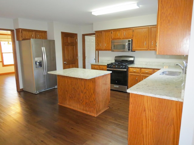 kitchen featuring light stone countertops, dark hardwood / wood-style flooring, stainless steel appliances, sink, and a center island