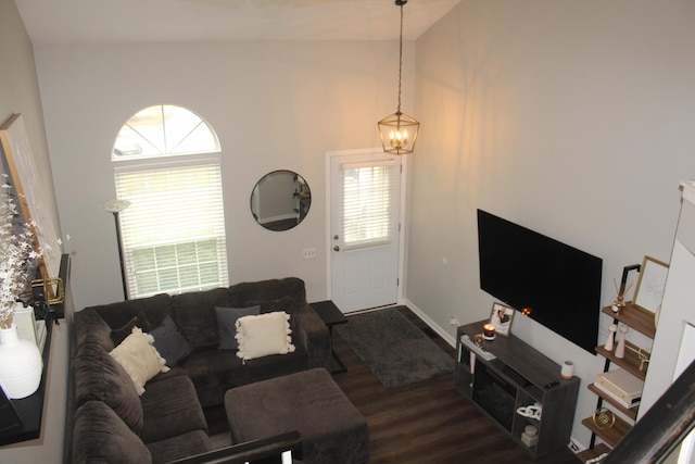 living room with lofted ceiling, dark wood-type flooring, and a notable chandelier