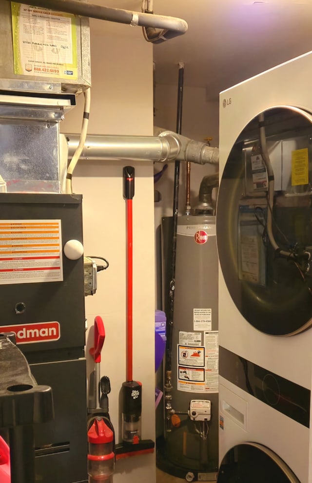 utility room featuring stacked washer / dryer and water heater