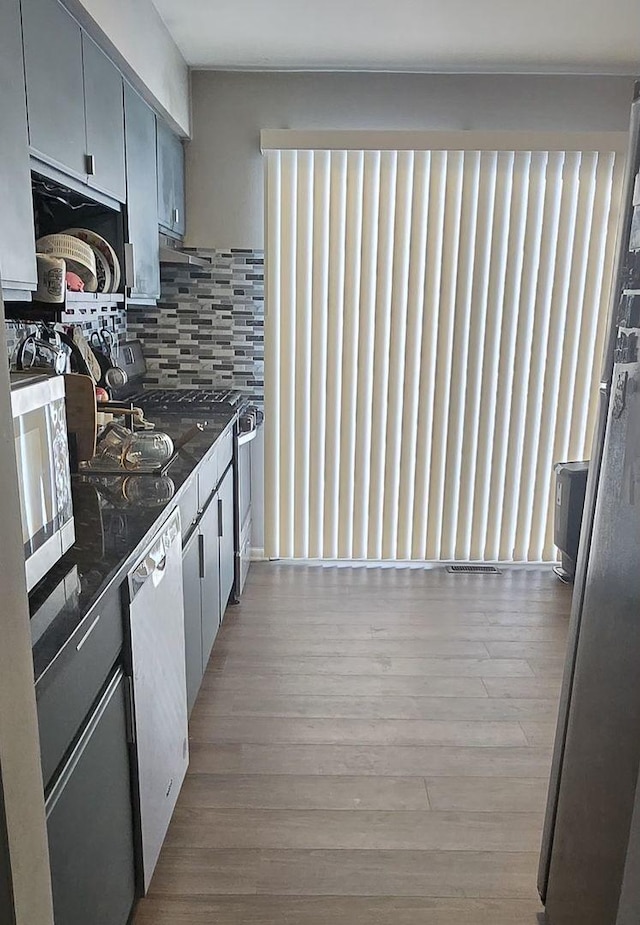 kitchen featuring dishwasher, decorative backsplash, and light hardwood / wood-style flooring