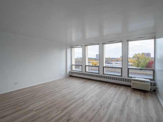 spare room with a baseboard heating unit and light wood-type flooring