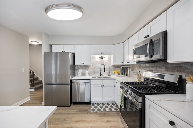 kitchen featuring light stone counters, sink, white cabinets, and stainless steel appliances