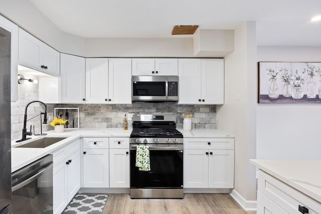 kitchen with sink, white cabinetry, stainless steel appliances, and tasteful backsplash