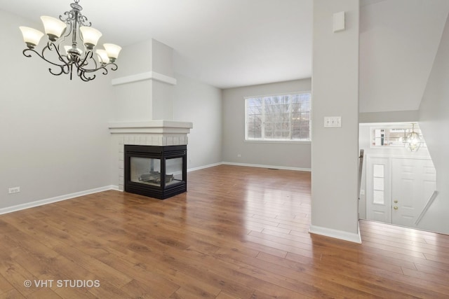 unfurnished living room featuring a fireplace, a notable chandelier, and hardwood / wood-style flooring