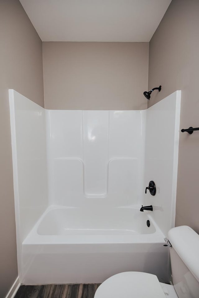 bathroom featuring hardwood / wood-style flooring, shower / bathing tub combination, and toilet