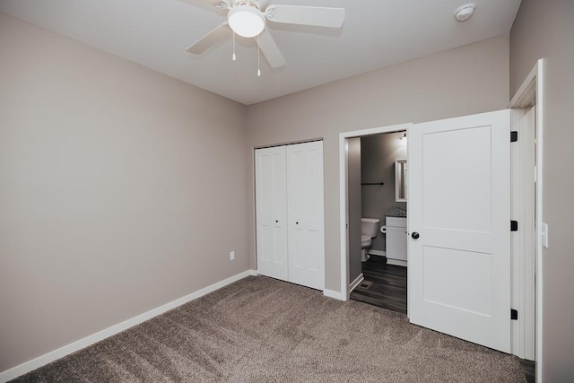 unfurnished bedroom featuring dark colored carpet, connected bathroom, a closet, and ceiling fan