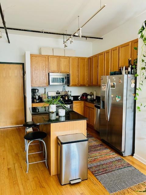 kitchen featuring a breakfast bar area, light wood-type flooring, and appliances with stainless steel finishes