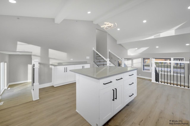 kitchen with vaulted ceiling with beams, a center island, light wood-type flooring, and white cabinetry