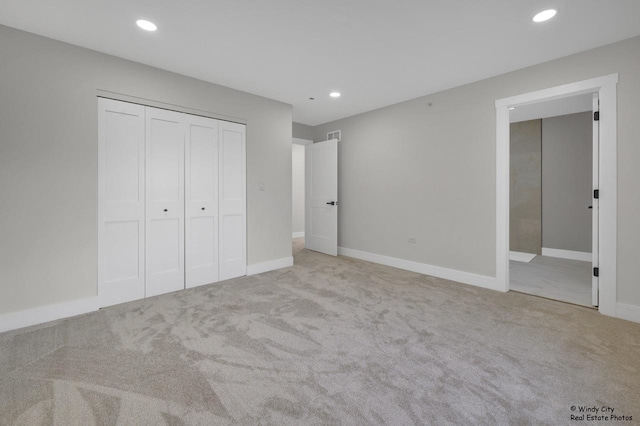 unfurnished bedroom featuring ensuite bath, a closet, and light colored carpet