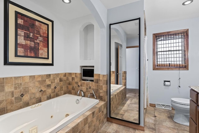 bathroom featuring vanity, toilet, and tiled tub