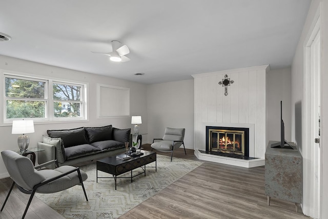 living room with ceiling fan, a fireplace, and hardwood / wood-style floors