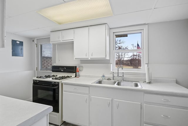 kitchen with a drop ceiling, electric panel, white cabinets, sink, and white range with gas cooktop