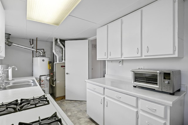 kitchen with sink, white cabinets, and gas water heater