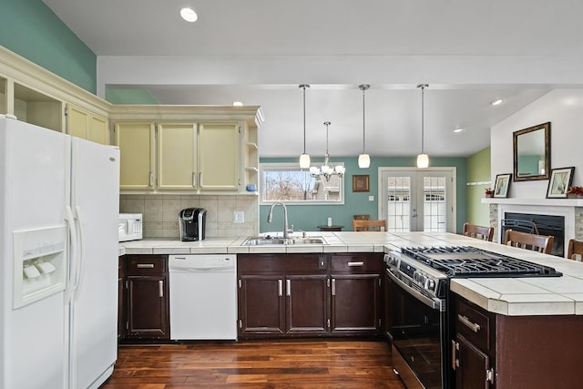 kitchen featuring pendant lighting, white appliances, sink, tasteful backsplash, and tile counters