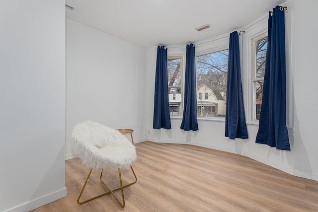 living area with visible vents, baseboards, and wood finished floors