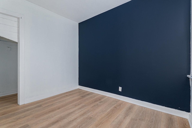 spare room with baseboards and light wood-type flooring