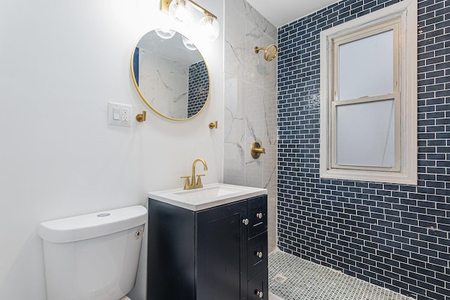 full bath featuring toilet, tiled shower, and vanity