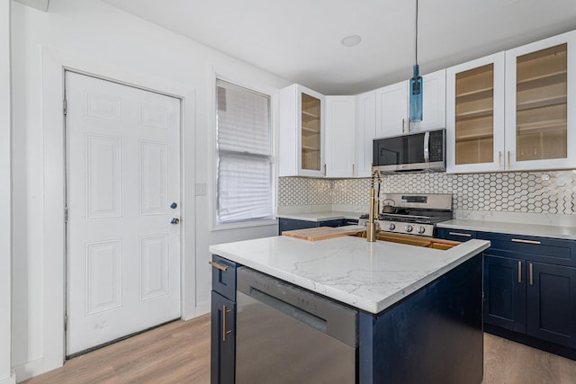 kitchen featuring an island with sink, backsplash, stainless steel appliances, light wood-style floors, and white cabinets