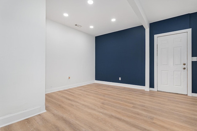 empty room with beamed ceiling, recessed lighting, baseboards, and light wood-style floors