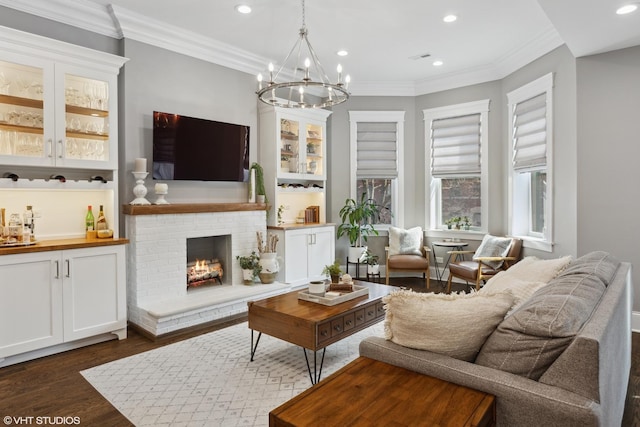 living room featuring a fireplace, ornamental molding, dark hardwood / wood-style floors, and a notable chandelier