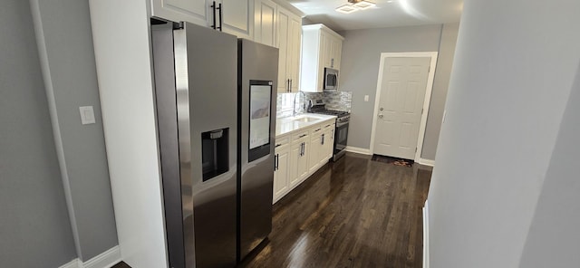 kitchen with backsplash, stainless steel appliances, white cabinetry, and dark wood-type flooring