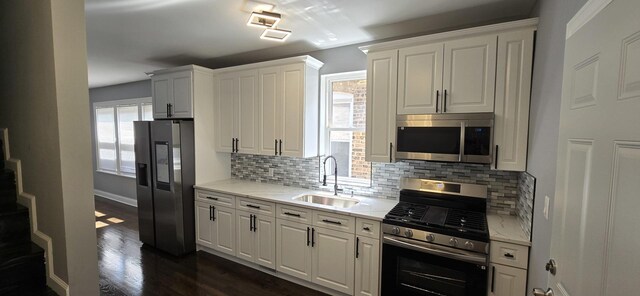 kitchen featuring decorative backsplash, appliances with stainless steel finishes, sink, dark hardwood / wood-style floors, and white cabinetry