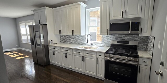 kitchen featuring white cabinetry, sink, light stone countertops, stainless steel appliances, and tasteful backsplash