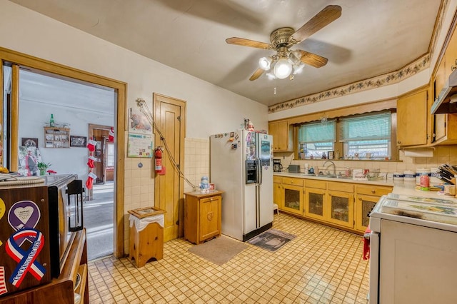 kitchen featuring ceiling fan, white refrigerator with ice dispenser, a wealth of natural light, and range