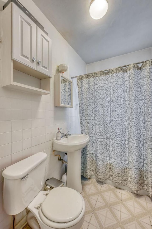 bathroom with a shower with curtain, tile walls, and toilet