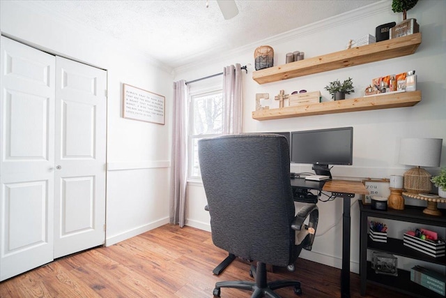 home office with a textured ceiling, light wood-type flooring, ceiling fan, and crown molding