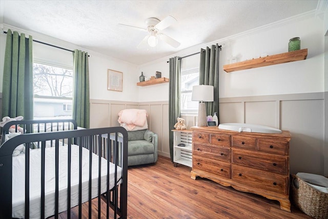 bedroom featuring multiple windows, ceiling fan, a crib, and ornamental molding