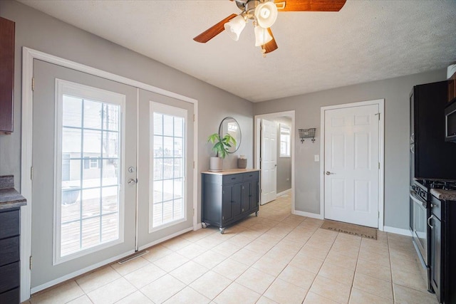 interior space with ceiling fan, french doors, light tile patterned flooring, and a textured ceiling