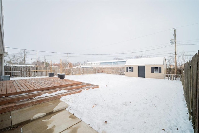 yard layered in snow with a deck and an outdoor structure