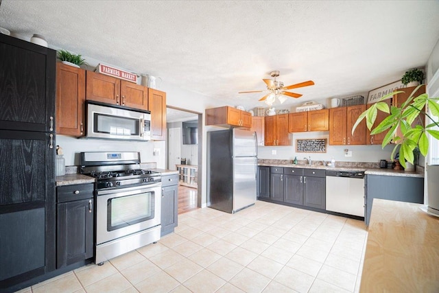 kitchen featuring ceiling fan, sink, a textured ceiling, light tile patterned floors, and appliances with stainless steel finishes