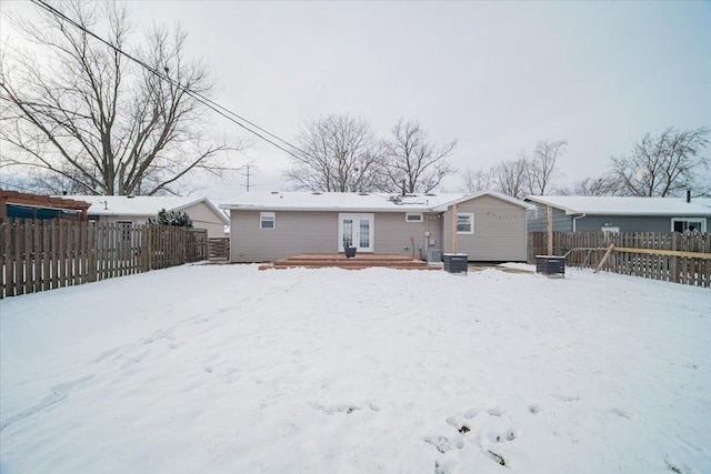 snow covered back of property featuring a deck and french doors