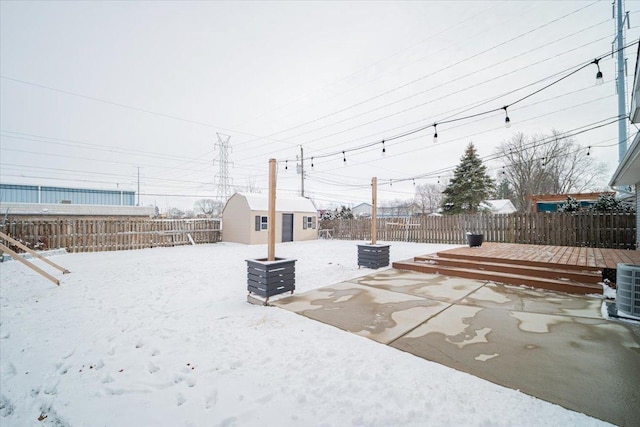 snowy yard with a shed and a deck